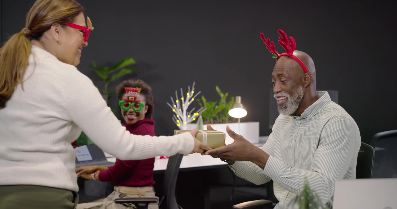 Senior African American man with antlers using laptop while coworker approaching