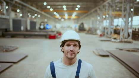 portrait of industrial worker in hardhat and overalls standing in factory