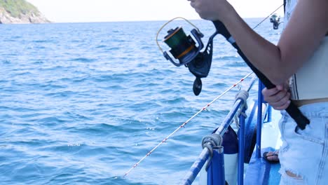 una persona pescando desde un barco en phuket, tailandia, mostrando vistas serenas del océano y acción de pesca enfocada