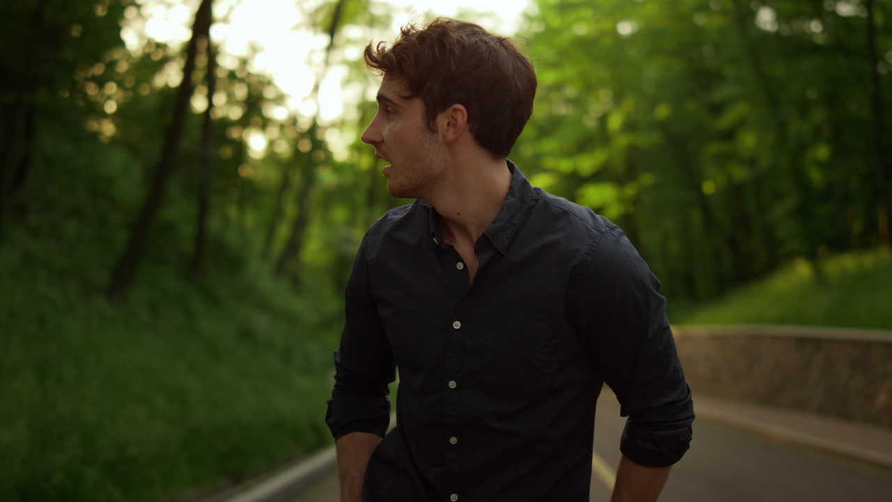 Handsome man spending time outdoors. Smiling guy having walk in park