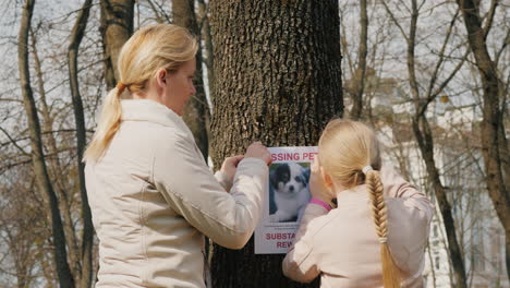 a woman with a child attaches a poster with information about the missing dog