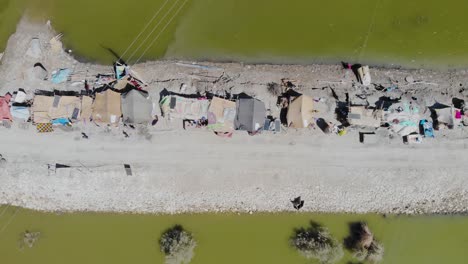 vista aérea de arriba hacia abajo sobre una franja elevada de tierra que alberga tiendas de campaña improvisadas rodeadas por un paisaje inundado en jacobabad, sindh