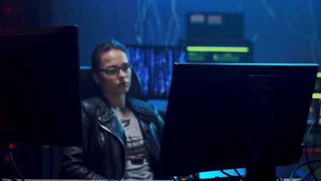 camera zoming in on the young software developer woman in glasses sitting in front of the computer screen and resting