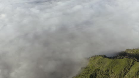 Aerial-view-of-low-hanging-clouds-covering-a-valley-in-Tengger,-East-Java,-Indonesia