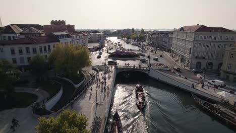 Schwenkaufnahme,-Die-Ein-Wunderschönes-Stadtbild-Am-Kreisverkehr-Von-Peaky-Maganos-Mit-Moliceiro-Booten-Auf-Der-Wasserstraße-Einfängt