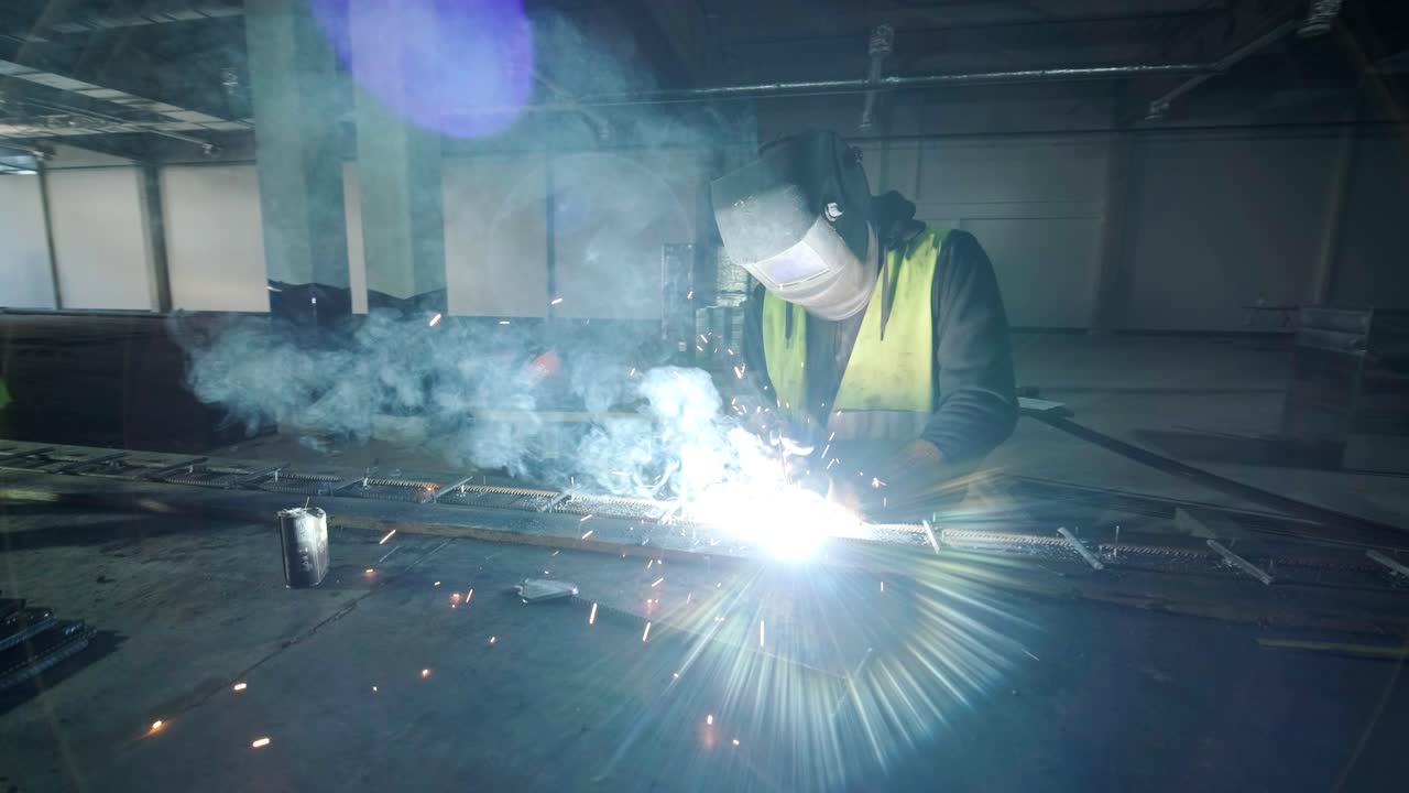 Professional welders are working in the factory wearing safety equipment. Metalwork manufacturing, industrial process.