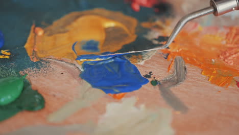 detail of a spatula mixing colors on a painter's palette