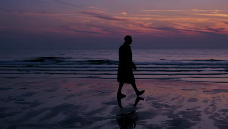 man walking on a beach at sunset