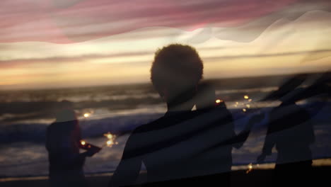 animation of waving flag of netherlands over group of friends having fun on the beach