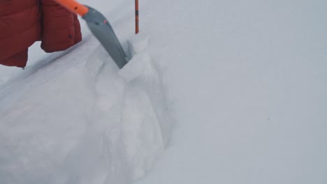 徒步旅行者在挖掘雪层,以检查雪地特征是否有雪崩危险,近距离观看