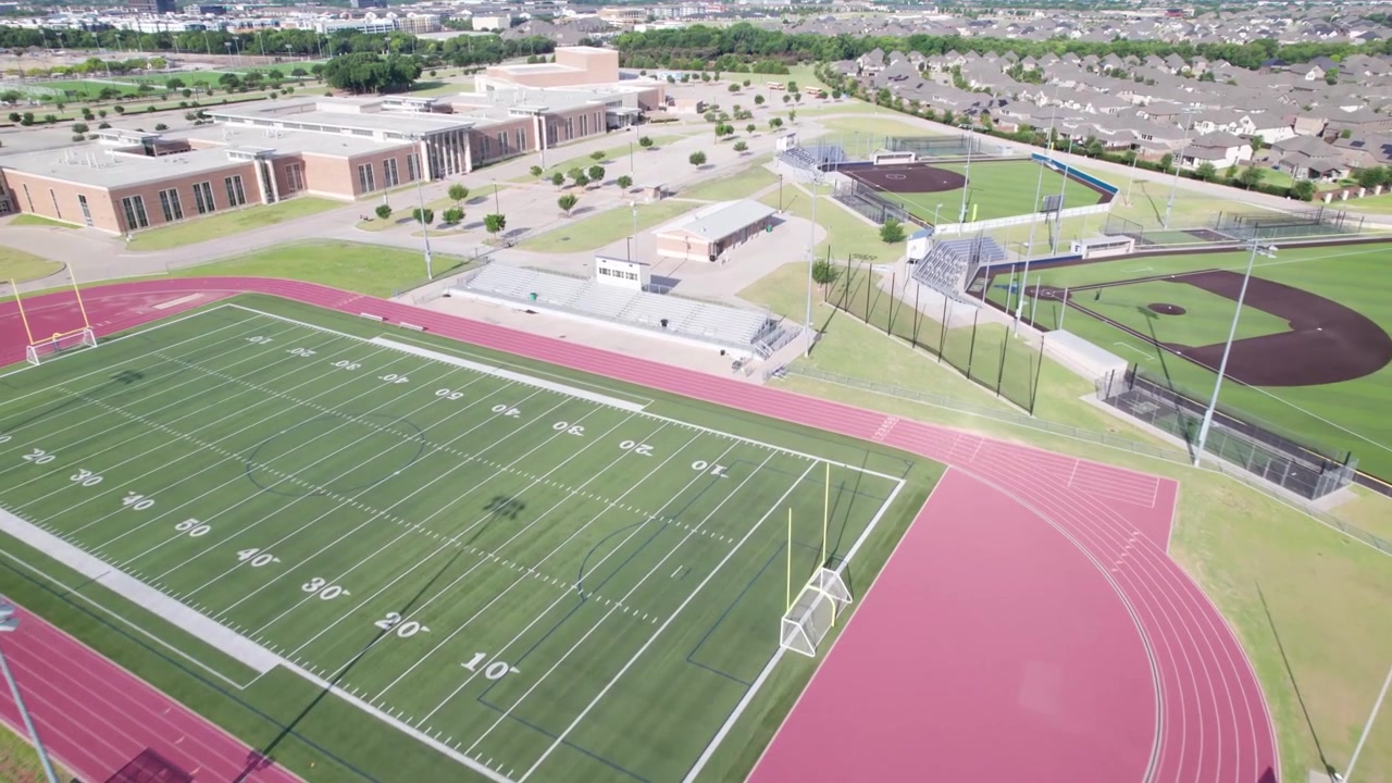 Aerial video of the Emerson High School sports fields. Camera approaches at an angle and shows the football field and baseball fields.