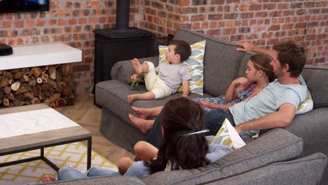 Familia-Sentarse-En-Un-Sofá-En-El-Salón-De-Planta-Abierta-Viendo-La-Televisión