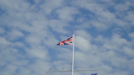 britische flagge an einem sonnigen tag mit wolken im höhepunkt einer gruppe von vögeln, die in zeitlupe fliegen