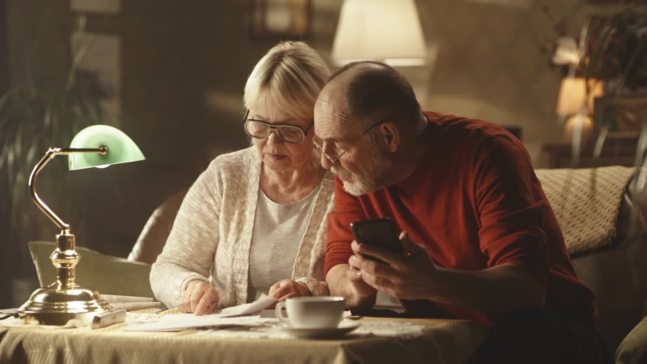 una pareja de ancianos comprobando las facturas de los servicios públicos por la noche.