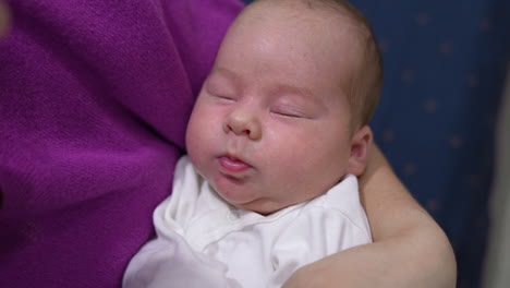 cute child sleeping sweetly and pressing his tiny lips in his sleep. adorable baby boy is resting peacefully in his mother's hands. close up.