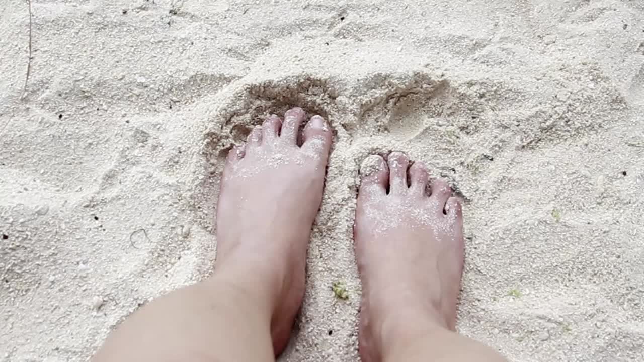 POV Burying bare feet in the fine golden sand, creating a relaxed beach atmosphere