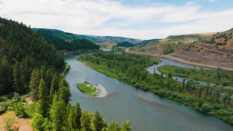 aerial view of a winding river through a lush forest valley