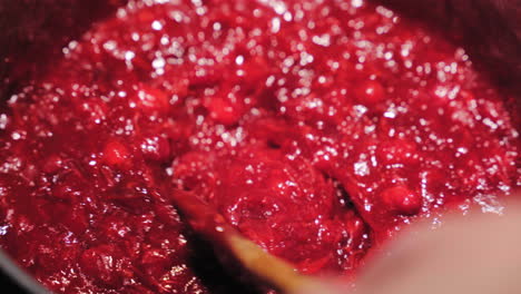 cooking and stirring cranberry sauce with wooden spoon