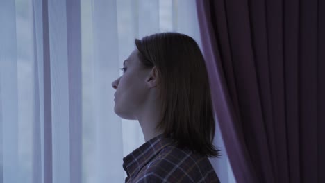 lonely woman looking out window from home thoughtful and unhappy.