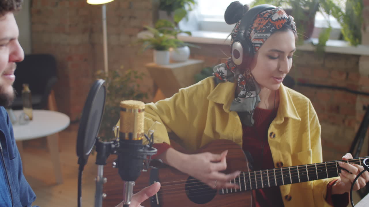 음악 듀오가 스튜디오에서 기타의 동반으로 노래하고 있습니다.