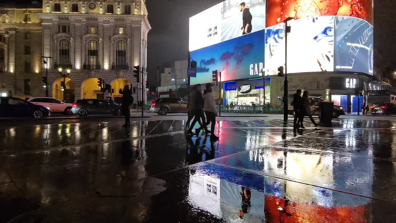 Piccadilly circus ads at night with few London citizens pedestrians, real time shot