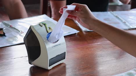 a person pulls tissue from a dispenser on a wooden table in a phuket restaurant, with natural lighting