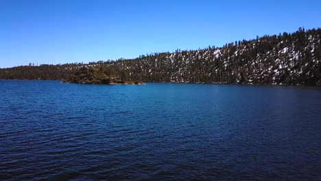 aerial drone, flying through tress, lake tahoe at emerald bay, snow mountains, sunny day, nevada, usa