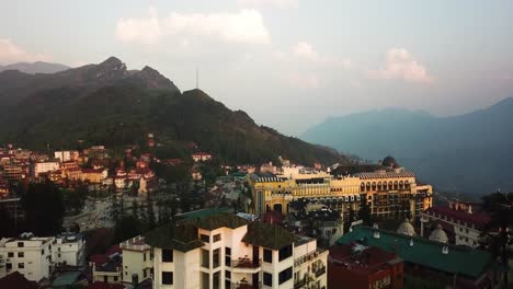 Drone-shot-of-an-Asian-town-within-the-mountains,-descending-down-to-an-apartment-building-in-Sapa-Vietnam