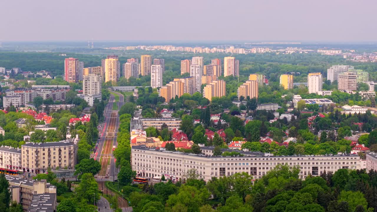 Wide aerial establishing of Zoliborz residential streets with distant Bielany district buildings, speckled light and cloud shadows