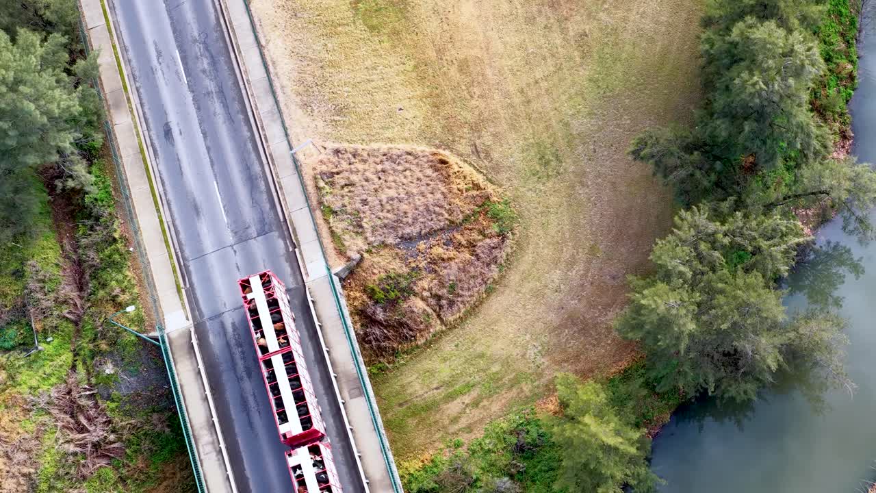 Overhead drone footage captures two trucks driving across a rural bridge in Coonabarabran, New South Wales, with natural landscape and soft daylight