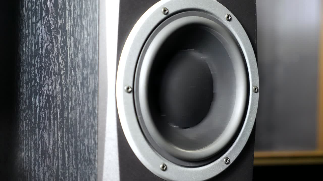 レコーディングスタジオで動くサブウーファーのクローズアップ。低周波の大きな音楽を聴いて脈動し振動する黒いスピーカー。現代のハイファイラウドスピーカーの振動板の動作。スローモーション