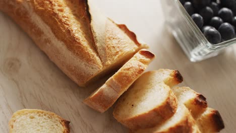 video de baguette, arándanos y cono de pino en una superficie de madera