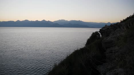 Full-shot,-sea-waves-on-the-side-of-the-cliff,-scenic-sunset-over-the-mountain-range-in-Antalya,-Turkey