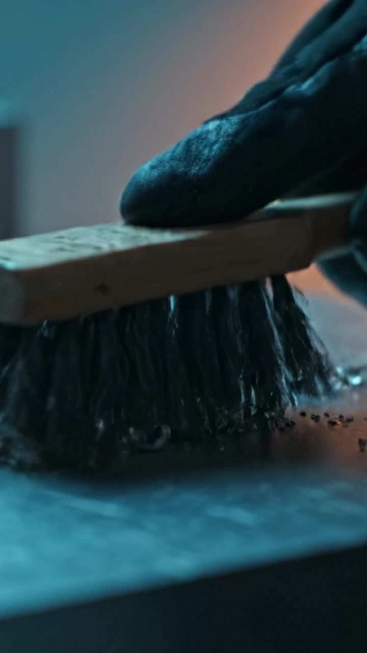 Detailní záběr kovových hoblin a kapek rozptýlených na dílenském stole, odrážejících světlo s uměleckou směsí modrých a teplých tónů, zachycující detaily řemeslné práce.