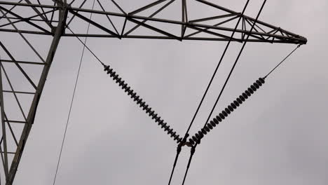 Close-up-of-electrical-insulators-and-high-tension-lines-on-electrical-transmission-tower