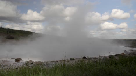 steamy geothermal vent, iceland with cloudy skies and grassy foreground