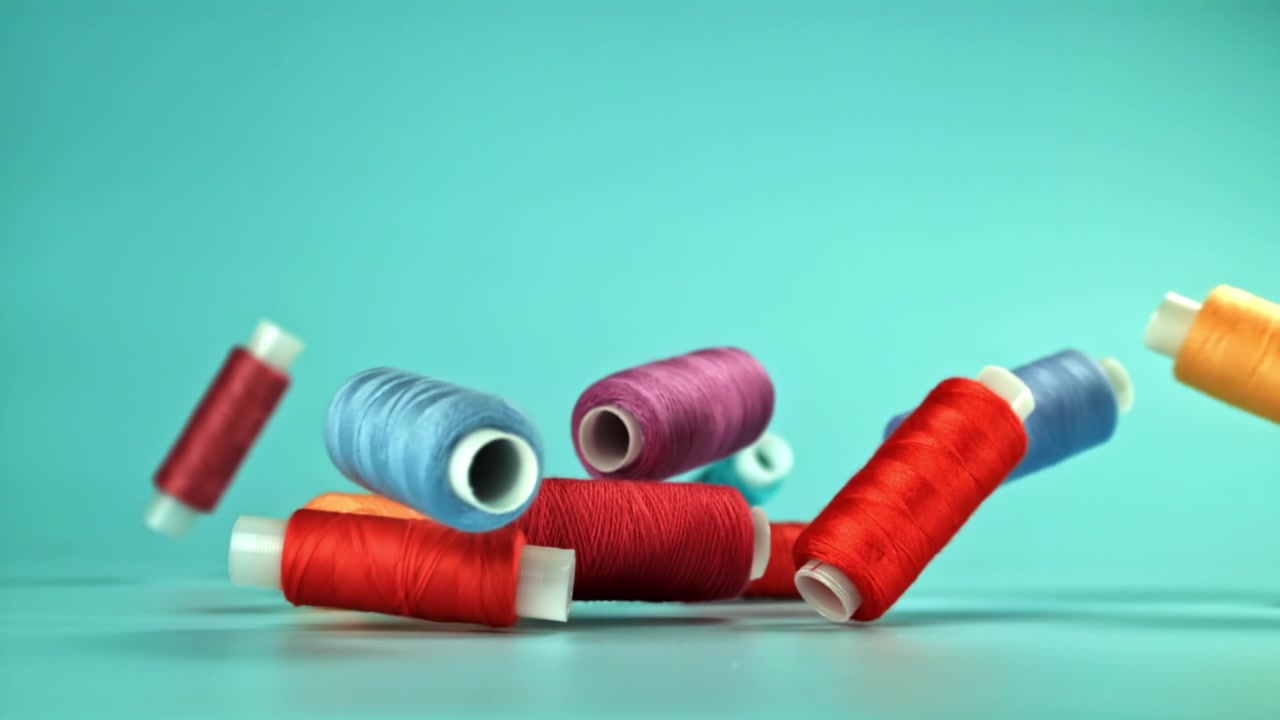 Colorful Sewing Thread Spools Falling in Slow Motion