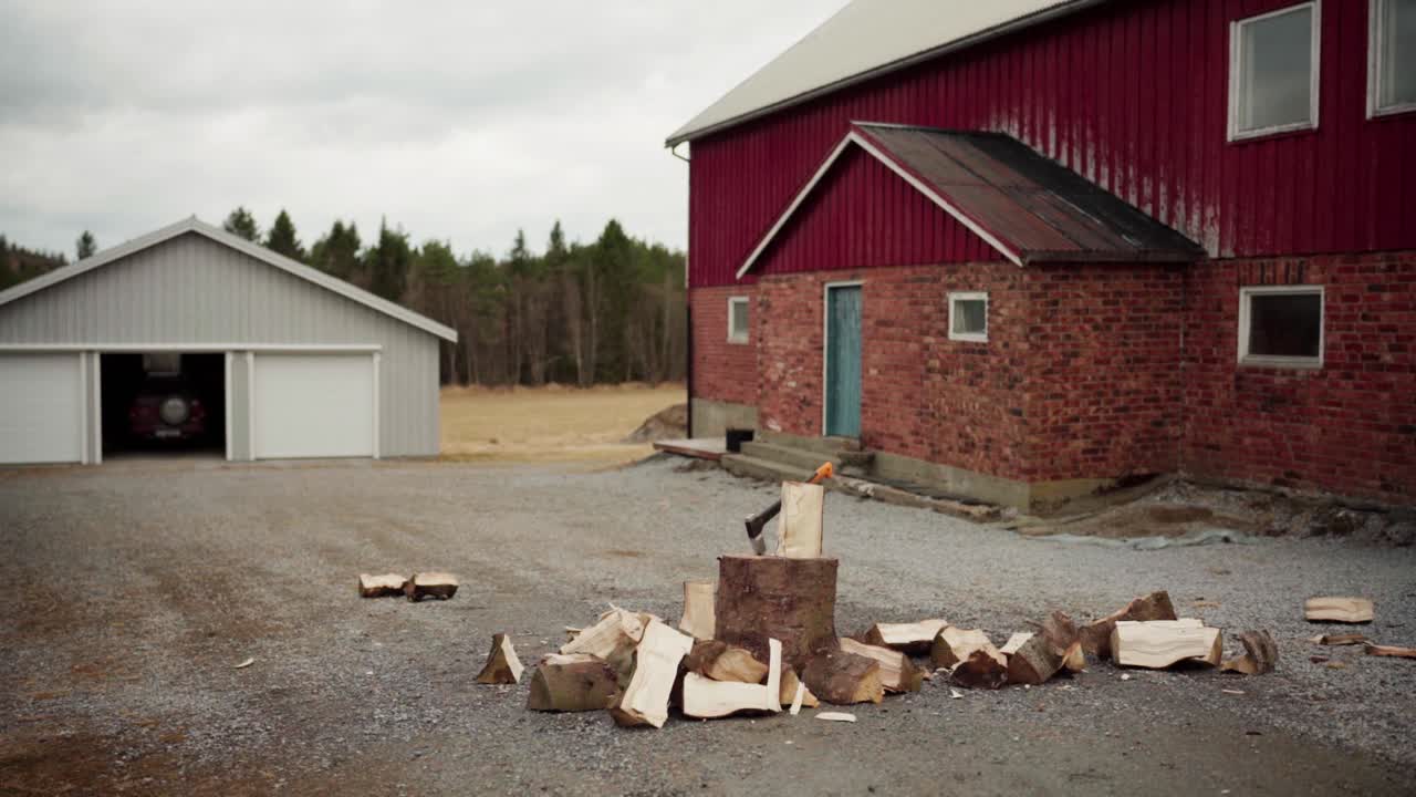 Mies kirveellä pilkkomassa polttopuita mökin edustalla. Timelapse.