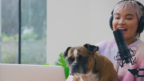 woman with pet french bulldog recording podcast or broadcasting on radio in studio at home