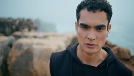 male athlete looking camera at cloudy seaside closeup. handsome fit guy listen