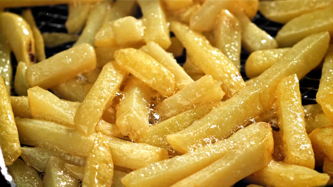 Patatas fritas doradas friéndose en aceite caliente burbujeante