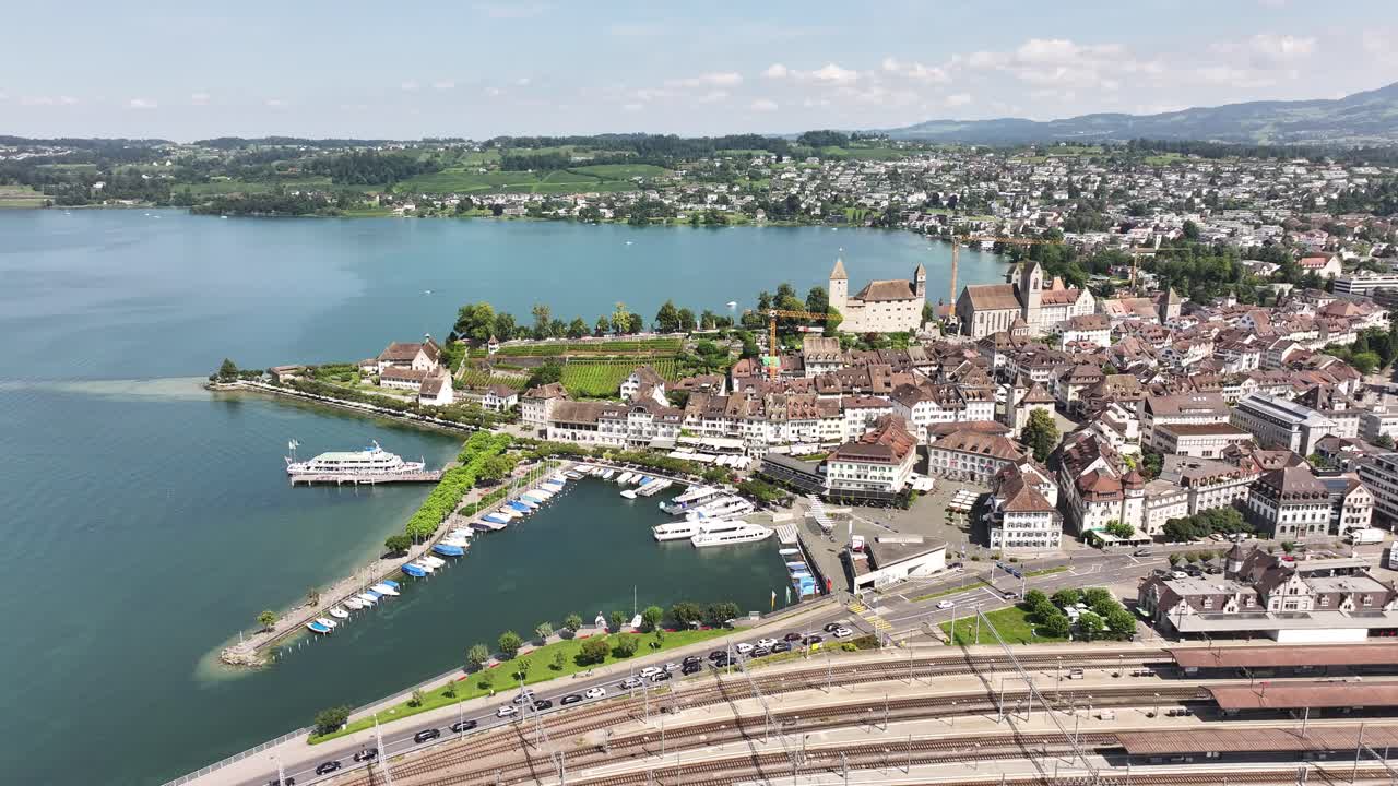 dron volando sobre la ciudad de rapperswil-jona o zürichsee, mostrando bahnhof rapperswil y el castillo en el fondo