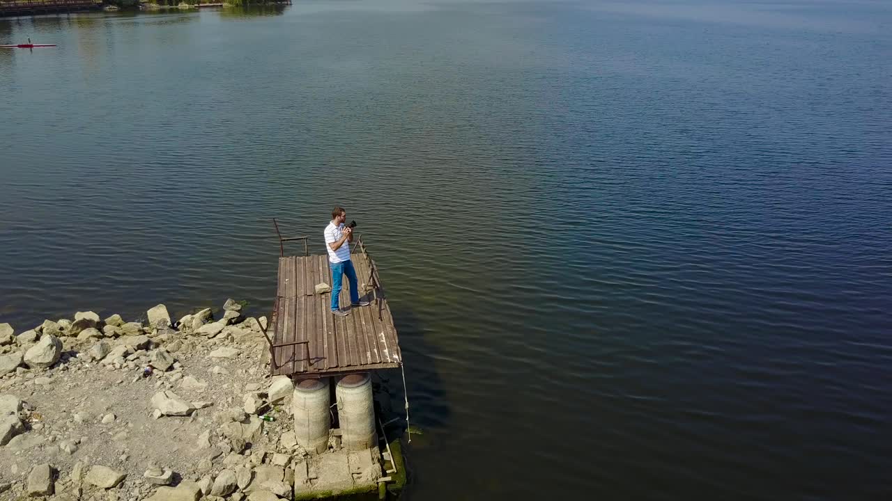 Male Photographer Near The Lake. Profesisonal photographer taking shot of beautiful nature near lake