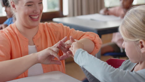 in school, female teacher and student practicing sign language together in classroom