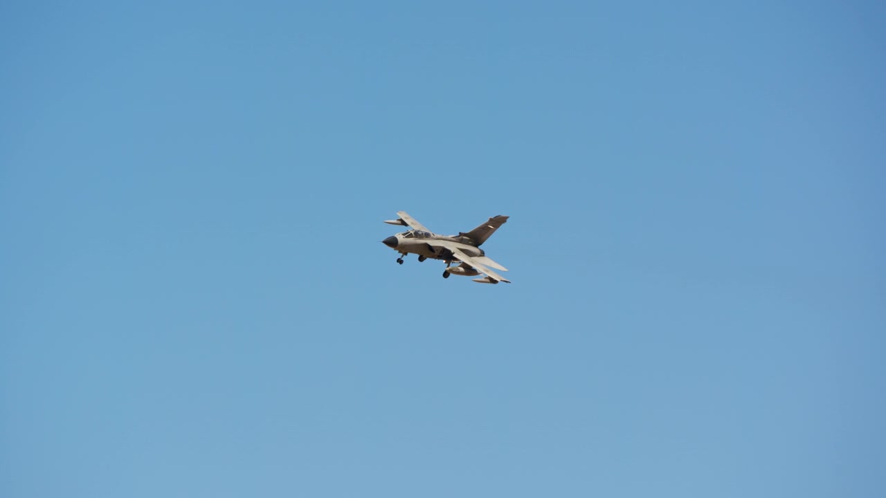 Combat jet descending to land against blue sky