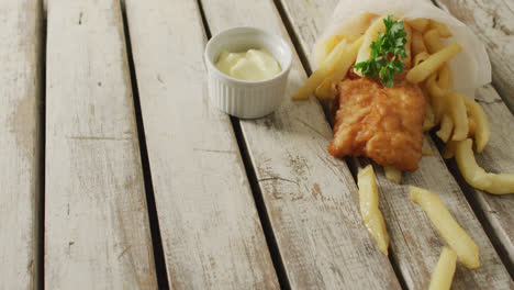 video of wrapped fish and chips with dip, on rustic table top with copy space