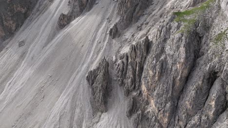 Drone-captures-Dolomites'-steep-cliffs-and-rocky-slopes,-tilting-upwards-and-moving-forward