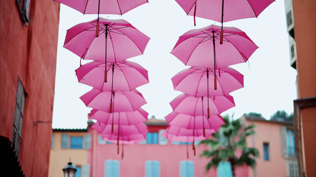 Rows of pink umbrellas above the streets of the old town in Grasse, France