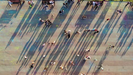 view from quadrocopter to people walking around on square summer at sunset