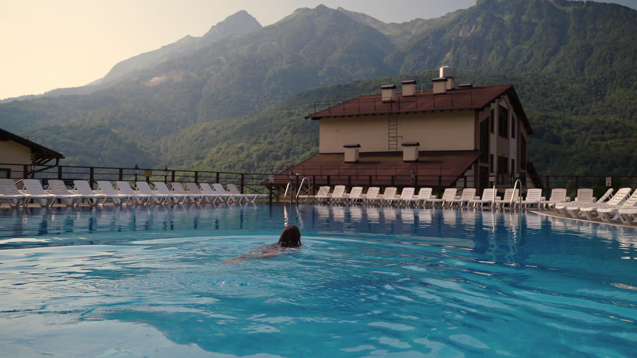 девушка плавает в бассейне горного курорта